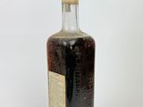 an old bottle of liquor sitting on top of a white surface