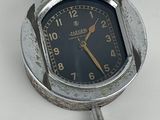 une horloge argentée avec un cadran noir sur un fond blanc