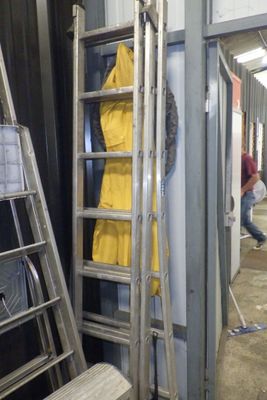 une échelle appuyée contre un mur, sur laquelle est posé un manteau jaune