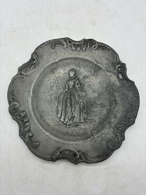 une assiette en argent sur laquelle est représentée une femme