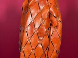 an orange leather jacket on a mannequin stand against a red background