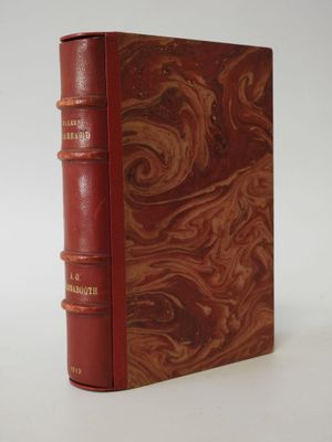 an old book with a red cover sitting on top of a white table