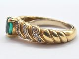 an image of a close up of a gold ring with a green stone