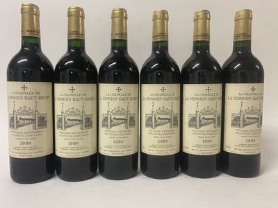 six bottles of wine are lined up on a white surface
