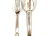 two silver spoons and a fork on a white surface