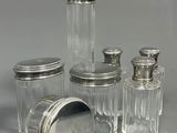quatre bocaux en verre avec des couvercles argentés, posés sur une surface grise