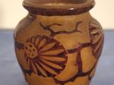 un vase marron orné d'un motif, posé sur une table bleue