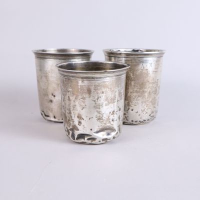 trois coupes en argent sont alignées les unes à côté des autres sur une surface blanche