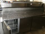 une photo d'une cuisine professionnelle équipée d'appareils électroménagers en acier inoxydable et de plans de travail en granit