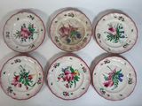 six assiettes ornées de motifs floraux posées sur une surface blanche