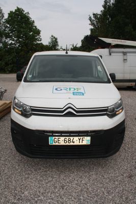 une camionnette blanche garée sur un parking, avec une remorque en arrière-plan