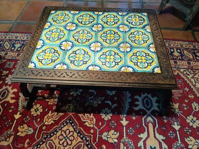 une table basse avec un plateau en carreaux colorés, posée sur un tapis