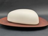 a white soap sitting on top of a wooden plate on a table