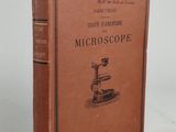 an old book with a microscope on it sitting on a table
