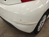 a white car that has been dented and is parked in a garage
