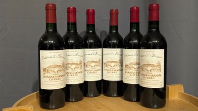four bottles of red wine sitting on top of a wooden barrel