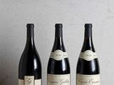 trois bouteilles de vin sont alignées sur une table en bois