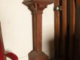 une chaise rouge dans un coin de la pièce, à côté d'une grande colonne en bois