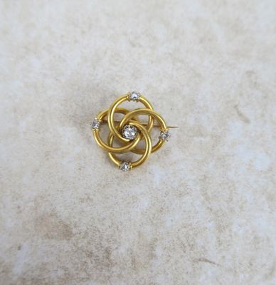 a close up of a gold and diamond broochle on a marble surface