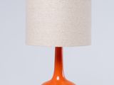 une lampe de table orange surmontée d'un abat-jour en lin