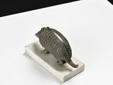 a silver sculpture of an armadile on a white stand