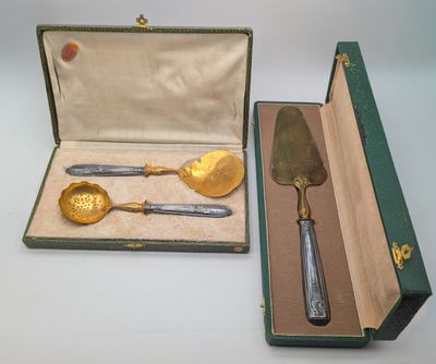 deux pièces d'argenterie dans un coffret vert posé sur une table