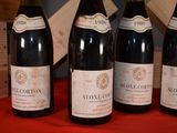 four bottles of wine are lined up on a red table