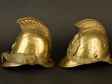 pair of antique brass roman helmet bookends on a black background