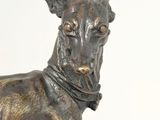 bronze statue of a dog with a collar and a collar around it ' s neck
