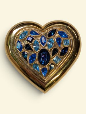 a gold heart shaped brooch with blue stones on it