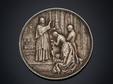 a silver coin with a woman and a man on it