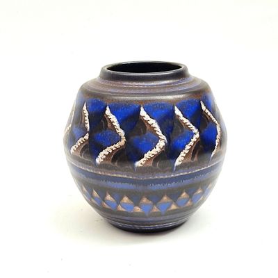 un vase bleu et noir posé sur une surface blanche