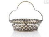 an antique silver basket with a handle on a white surface