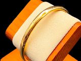 a gold bracelet on a wooden stand with a ring on top of it