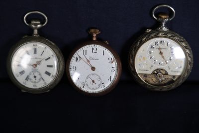 trois montres de poche anciennes sont alignées sur une surface noire