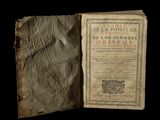 an old book opened to reveal a page of text on a black background