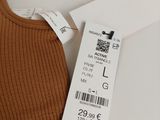 the label on the top of a brown sweater hangs on a white hanger