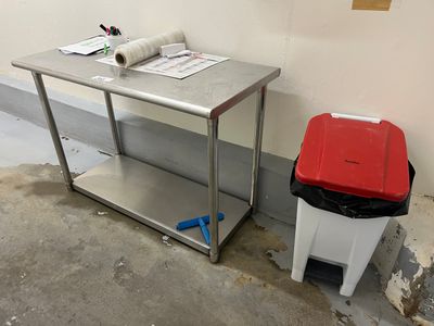 une poubelle posée à côté d'une table sur laquelle se trouve un rouleau de papier