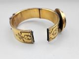 a close up of a gold bracelet on a white surface