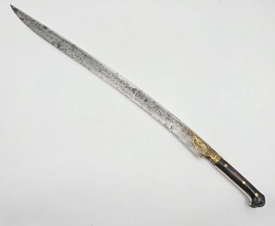 un vieux couteau au manche doré posé sur une surface blanche