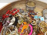 a wooden bowl filled with lots of jewelry on a table