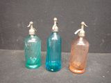 three different colored glass bottles sitting next to each other