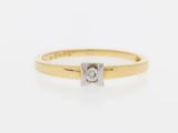 a yellow gold ring with a single diamond in the center
