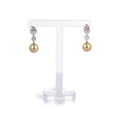 une paire de boucles d'oreilles en perles et diamants, présentée sur un présentoir
