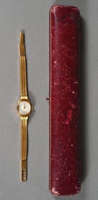 une montre en or et un étui rouge posés sur une table
