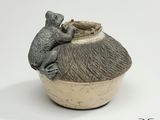un petit vase sur lequel est perchée une souris