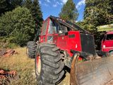a tractor that is sitting in the grass with a bulldozer behind it