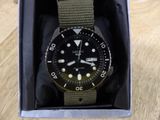 a black and green watch in a box on a wooden table