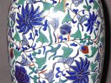un vase bleu et blanc orné de fleurs et de feuilles