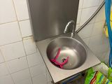 un lavabo dans un coin de la salle de bains, avec un tuyau bleu